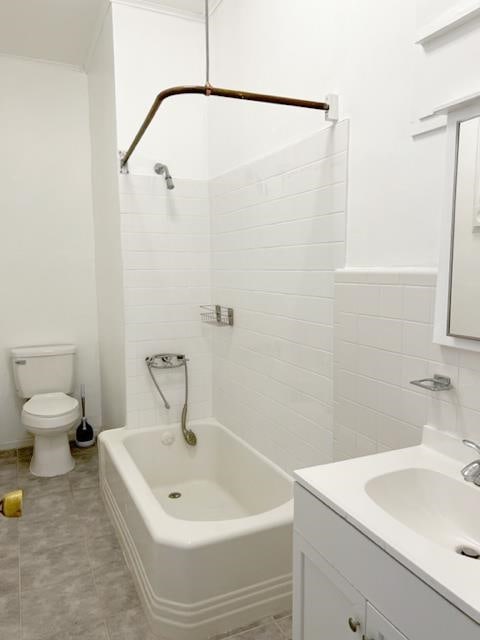 full bathroom with tile walls, tiled shower / bath, toilet, and vanity