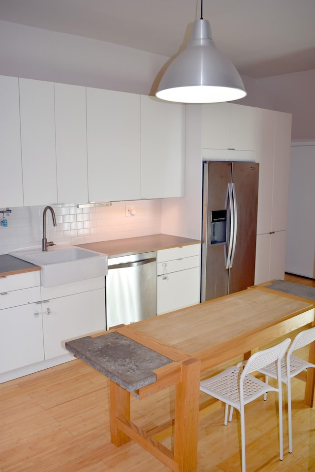 kitchen featuring white cabinetry, sink, appliances with stainless steel finishes, tasteful backsplash, and decorative light fixtures