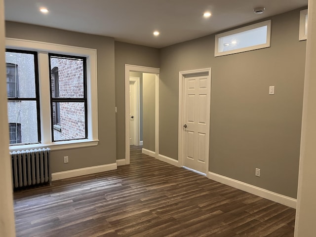 spare room with dark hardwood / wood-style flooring and radiator heating unit