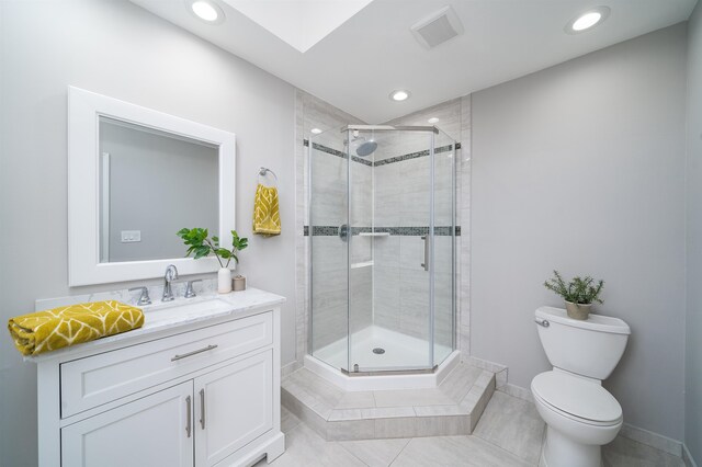 bathroom featuring toilet, vanity, an enclosed shower, and tile patterned floors