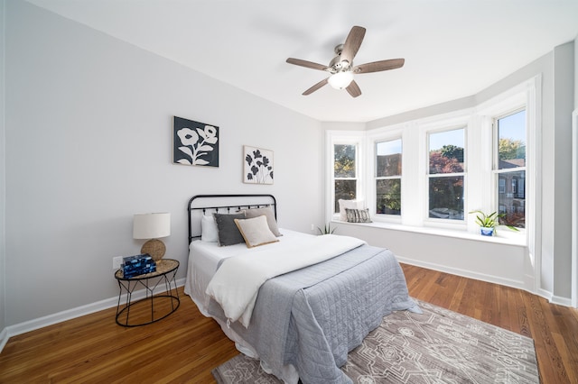 bedroom featuring ceiling fan, wood-type flooring, and multiple windows