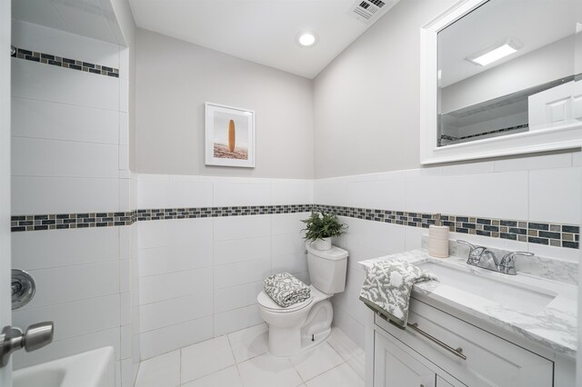 full bathroom featuring shower / tub combination, tile patterned flooring, vanity, toilet, and tile walls