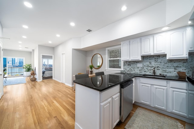 kitchen featuring light hardwood / wood-style floors, white cabinetry, sink, kitchen peninsula, and stainless steel dishwasher