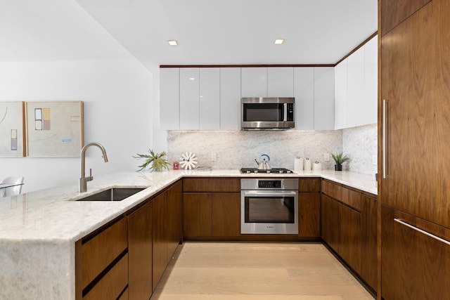 75 Park Ln S Unit 3402, Jersey City, NJ 07310 - kitchen featuring stainless steel appliances, a peninsula, white cabinets, light stone countertops, and backsplash