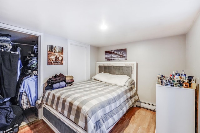 bedroom featuring a closet, hardwood / wood-style floors, and a baseboard radiator