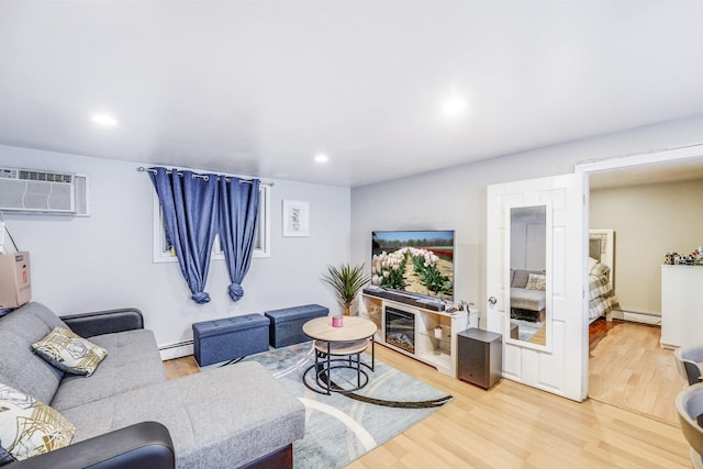 living room with baseboard heating, a wall mounted AC, and light hardwood / wood-style floors