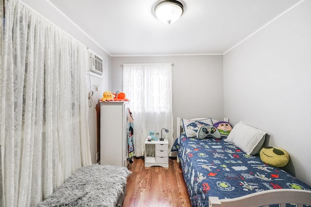 bedroom featuring hardwood / wood-style flooring, a wall mounted air conditioner, and ornamental molding