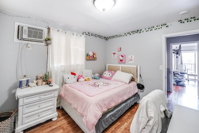 bedroom with hardwood / wood-style floors and an AC wall unit