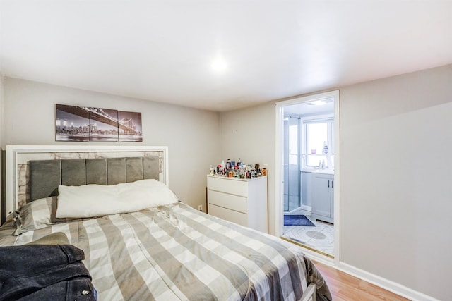 bedroom featuring ensuite bathroom, a fireplace, and hardwood / wood-style flooring