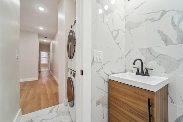 450 1st St Unit 2, Hoboken, NJ 07030 - bathroom with stacked washing machine and dryer, vanity, recessed lighting, tile walls, and baseboards