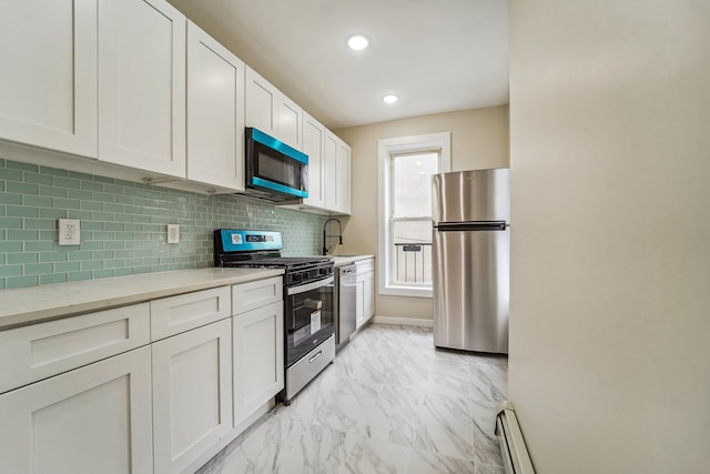 450 1st St Unit 2, Hoboken, NJ 07030 - kitchen featuring appliances with stainless steel finishes, light countertops, light marble finish flooring, white cabinetry, and decorative backsplash