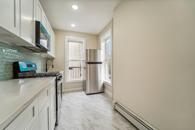 450 1st St Unit 2, Hoboken, NJ 07030 - kitchen featuring appliances with stainless steel finishes, a baseboard heating unit, light marble finish floors, baseboards, and white cabinets