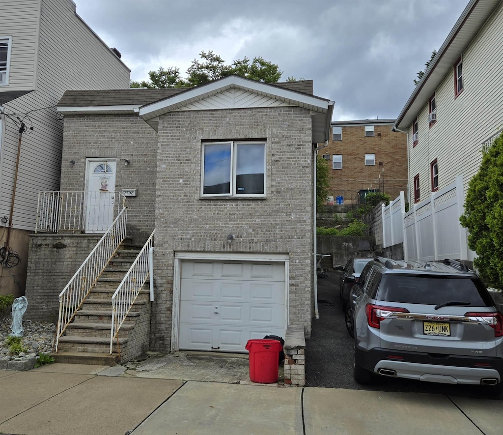 7502 Cottage Ave, North Bergen, NJ 07047 - view of front of property featuring an attached garage, brick siding, and driveway