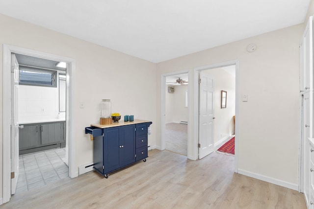 82 E 24th St, Bayonne, NJ 07002 - kitchen featuring blue cabinets, light wood-style floors, light countertops, ceiling fan, and a baseboard heating unit
