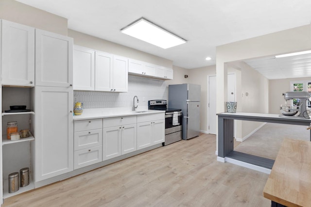 82 E 24th St, Bayonne, NJ 07002 - kitchen featuring appliances with stainless steel finishes, light countertops, light wood-style flooring, tasteful backsplash, and white cabinets