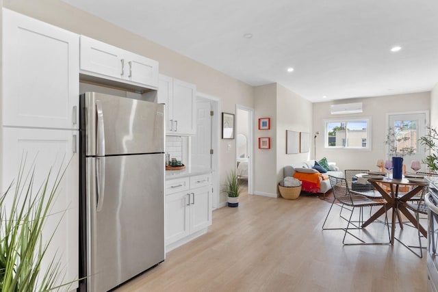 82 E 24th St, Bayonne, NJ 07002 - kitchen with freestanding refrigerator, an AC wall unit, white cabinets, light wood-type flooring, and recessed lighting