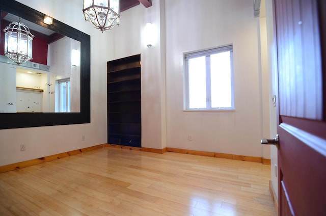 spare room featuring an inviting chandelier, wood finished floors, and a towering ceiling