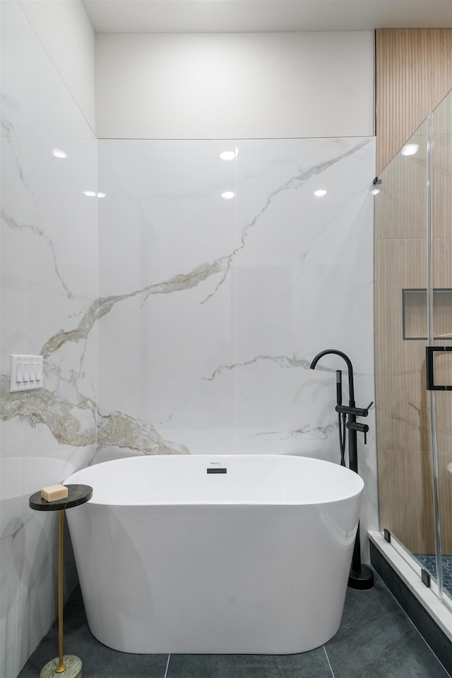 bathroom with a stall shower, a soaking tub, tile walls, and tile patterned floors