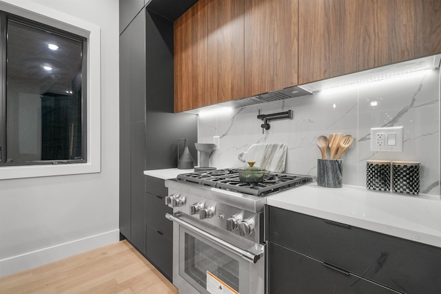 kitchen with light countertops, high end stainless steel range oven, modern cabinets, and light wood-style floors