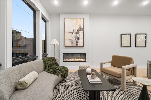 living room featuring a glass covered fireplace, baseboards, and recessed lighting