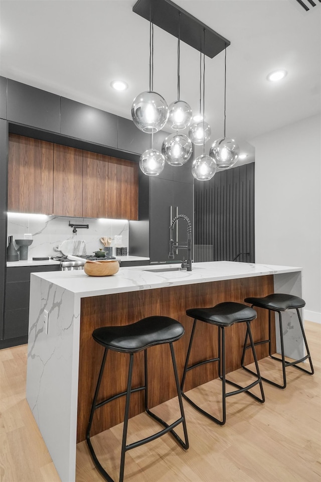 kitchen with a large island with sink, a sink, backsplash, and modern cabinets