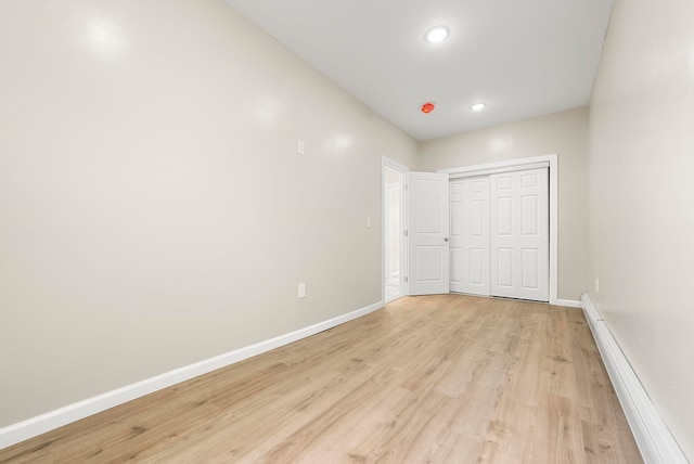 unfurnished bedroom with light wood-type flooring, recessed lighting, a closet, baseboards, and baseboard heating