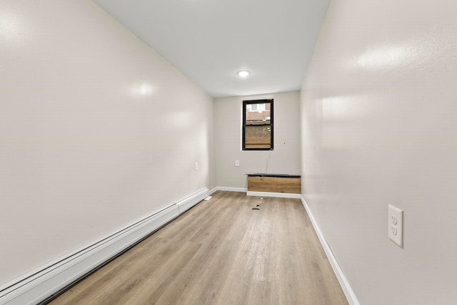 unfurnished room featuring light wood-style flooring, baseboards, and a baseboard radiator