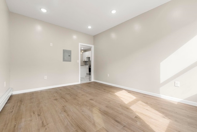 empty room featuring recessed lighting, light wood-type flooring, baseboards, and baseboard heating