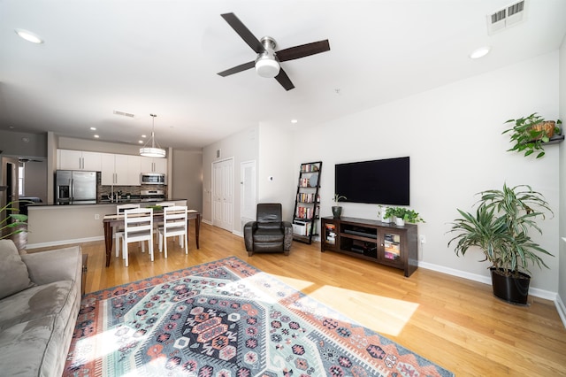 living area featuring a ceiling fan, light wood-type flooring, recessed lighting, and baseboards