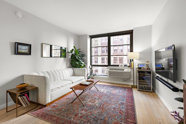 living area featuring light wood-type flooring, beverage cooler, and baseboards