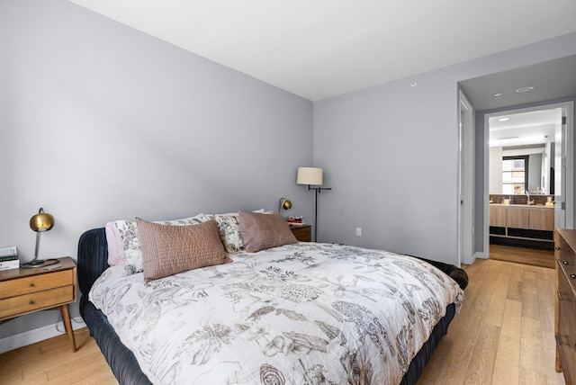 bedroom with baseboards, a sink, and light wood finished floors