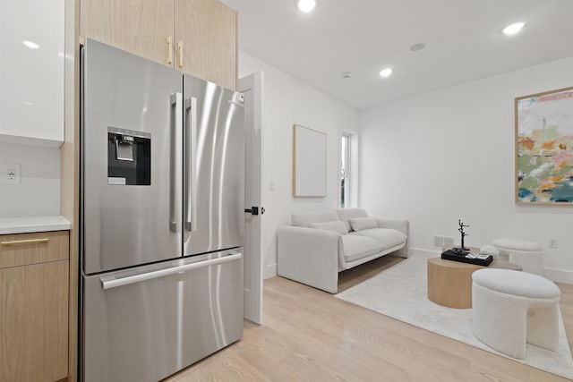 kitchen with light wood finished floors, stainless steel refrigerator with ice dispenser, open floor plan, recessed lighting, and light countertops