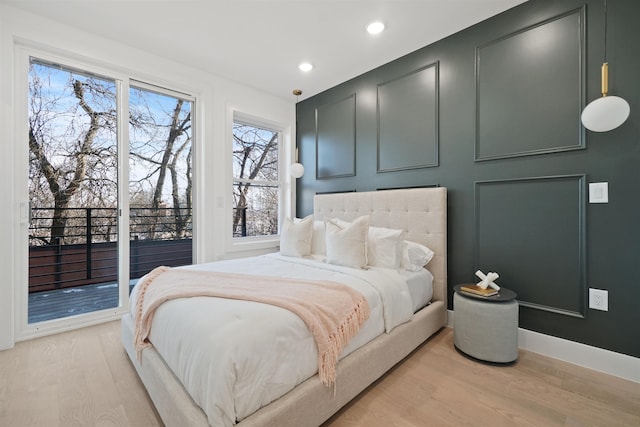 bedroom featuring access to exterior, baseboards, light wood-type flooring, recessed lighting, and a decorative wall