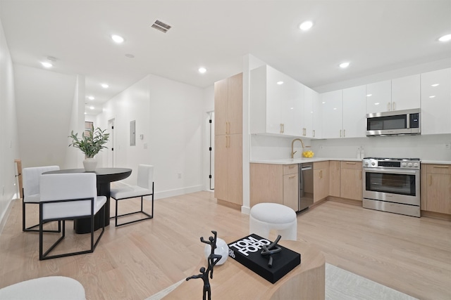 kitchen with visible vents, stainless steel appliances, light wood-style floors, and modern cabinets