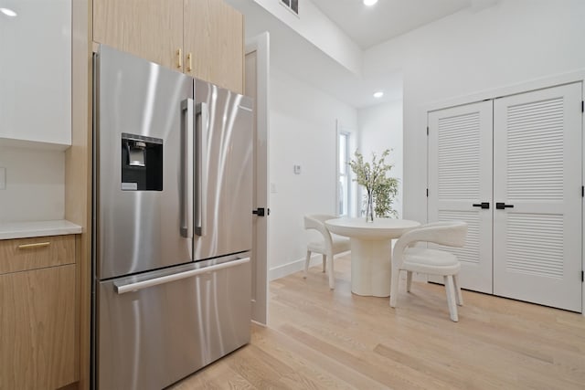 kitchen featuring visible vents, light wood finished floors, stainless steel fridge with ice dispenser, light countertops, and modern cabinets