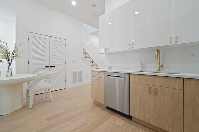 kitchen featuring visible vents, a sink, stainless steel dishwasher, modern cabinets, and light wood-type flooring