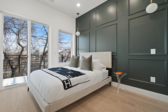 bedroom featuring a decorative wall, recessed lighting, and light wood-type flooring