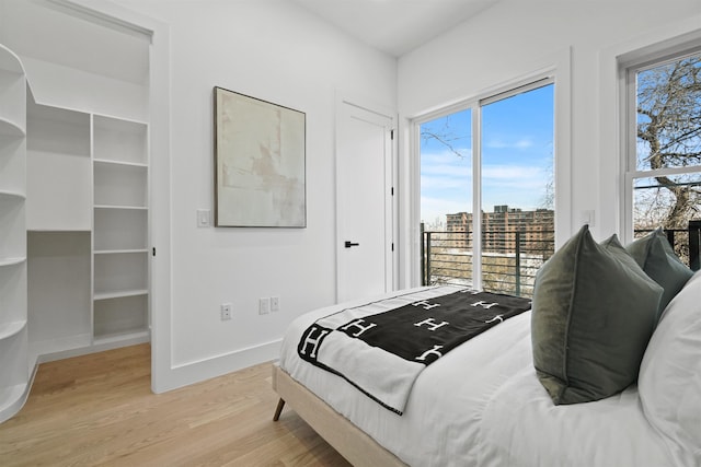 bedroom featuring access to exterior, wood finished floors, and baseboards