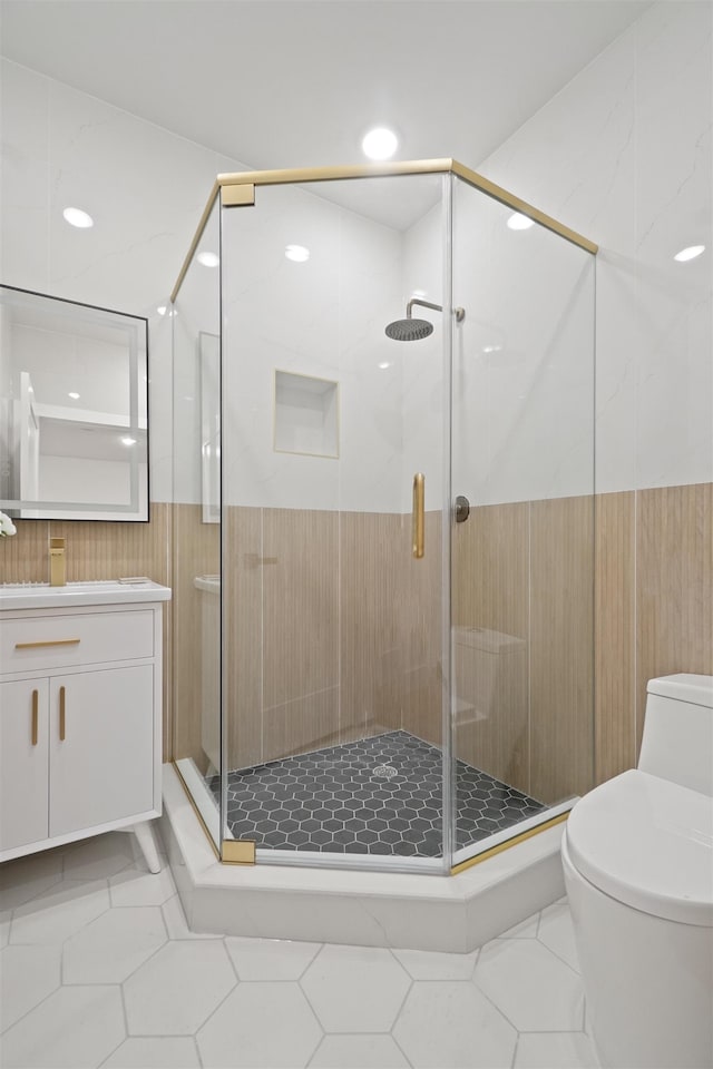 bathroom featuring tile patterned flooring, a stall shower, toilet, and vanity