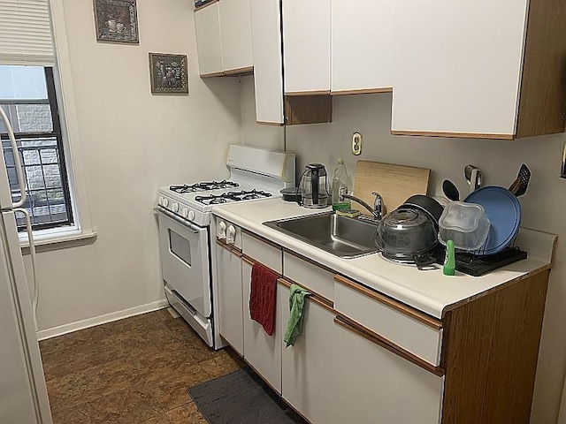 kitchen with white cabinets, light countertops, white range with gas stovetop, and a sink