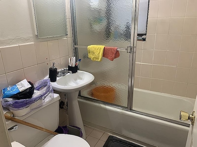 bathroom with tile patterned flooring, tile walls, toilet, and enclosed tub / shower combo