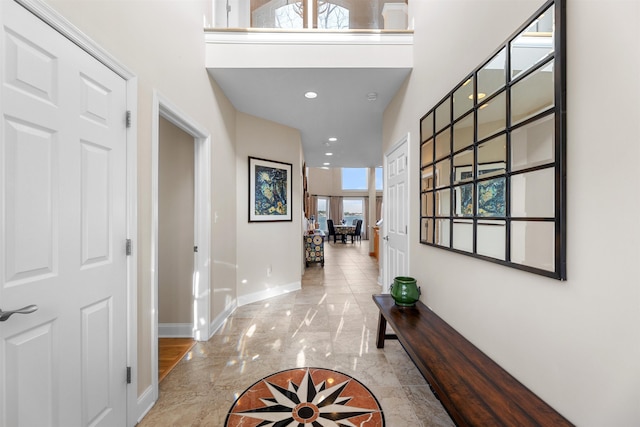 hall featuring baseboards, marble finish floor, a towering ceiling, and recessed lighting