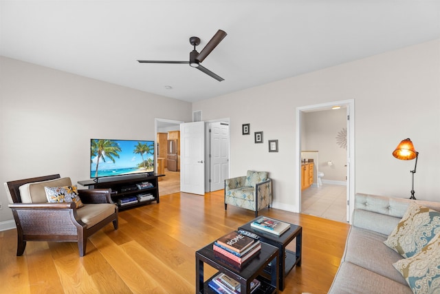 living area featuring a ceiling fan, baseboards, and wood finished floors