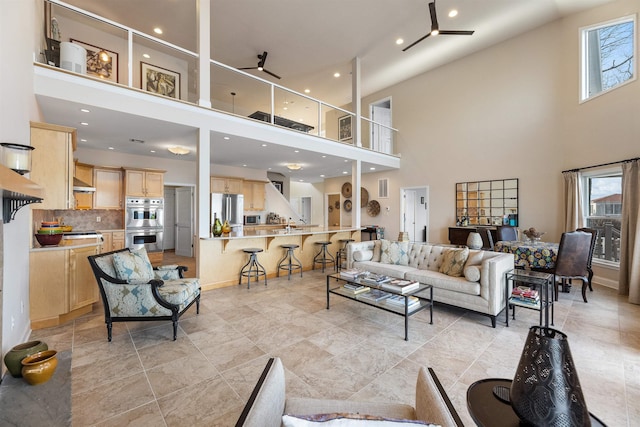 living area with visible vents, baseboards, recessed lighting, a ceiling fan, and a high ceiling