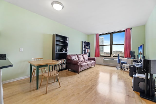 living room with a wall unit AC and light hardwood / wood-style floors