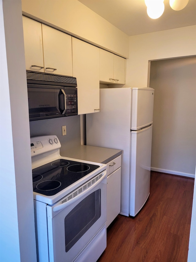 kitchen with white appliances, dark hardwood / wood-style floors, and white cabinetry