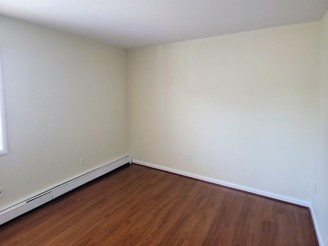 spare room with dark wood-type flooring and baseboard heating