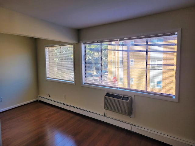 spare room featuring a baseboard heating unit, a wall unit AC, and dark hardwood / wood-style floors