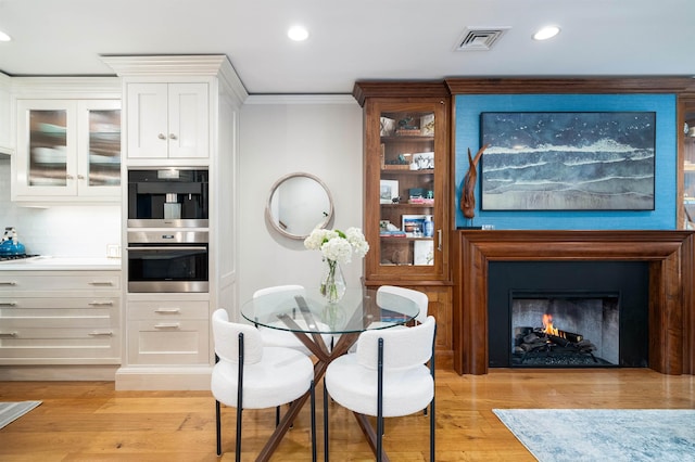 249 Grove St Unit 1, Jersey City, NJ 07302 - dining space featuring light wood-type flooring, recessed lighting, crown molding, and a warm lit fireplace