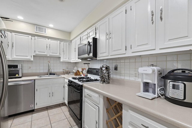 kitchen featuring light tile patterned floors, stainless steel appliances, light countertops, white cabinetry, and a sink